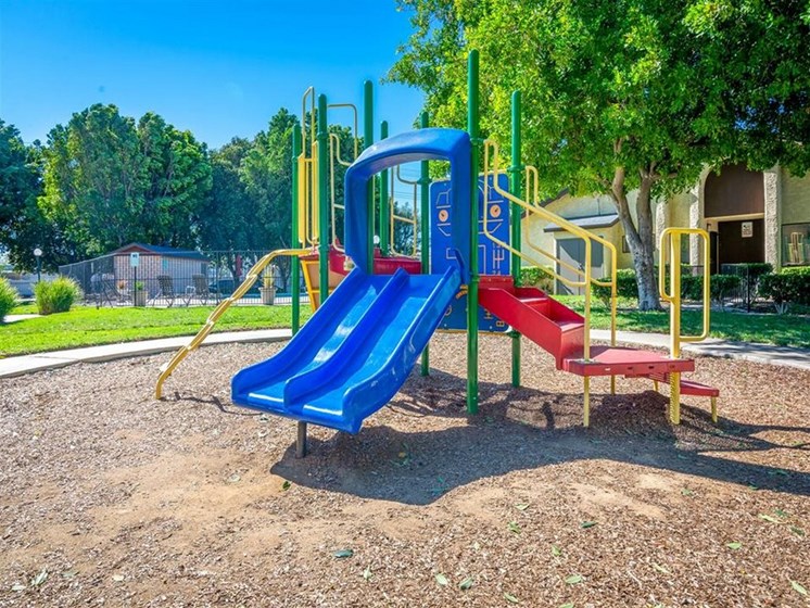 a playground with a blue slide and red and blue chairs